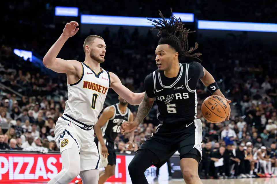 San Antonio Spurs guard Stephon Castle (5) dribbles the ball around Denver Nuggets guard Christian Braun (0) at Frost Bank Center in San Antonio on Thursday, March 12, 2026.