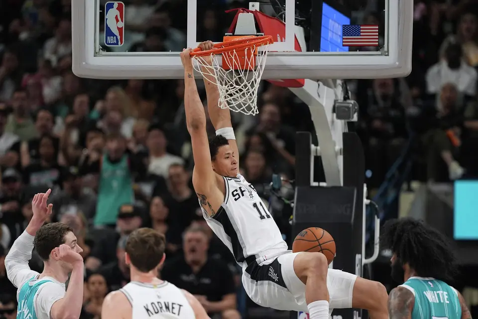 San Antonio Spurs forward Carter Bryant (11) scores past Charlotte Hornets center Ryan Kalkbrenner, left, during the second half of an NBA basketball game in San Antonio, Saturday, March 14, 2026. (AP Photo/Eric Gay)