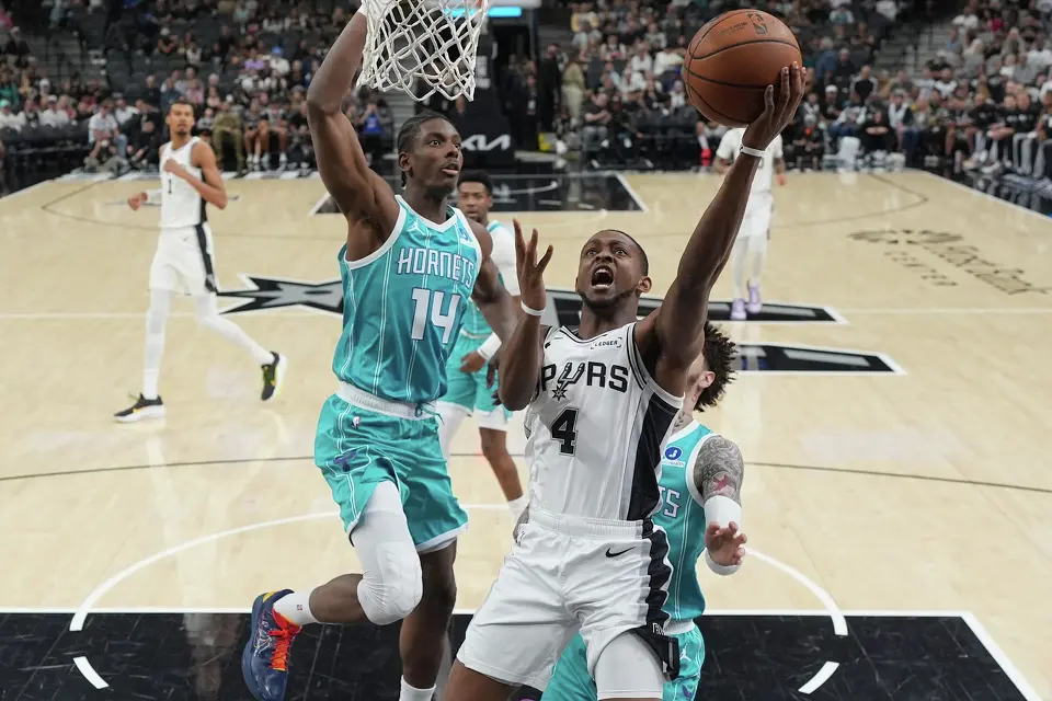 San Antonio Spurs guard De'Aaron Fox (4) drives to the basket past Charlotte Hornets forward Moussa Diabate (14) during the first half of an NBA basketball game in San Antonio, Saturday, March 14, 2026. (AP Photo/Eric Gay)