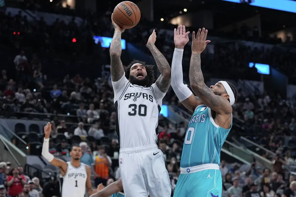San Antonio Spurs forward Julian Champagnie (30) shoots over Charlotte Hornets forward Miles Bridges (0) during the first half of an NBA basketball game in San Antonio, Saturday, March 14, 2026. (AP Photo/Eric Gay)