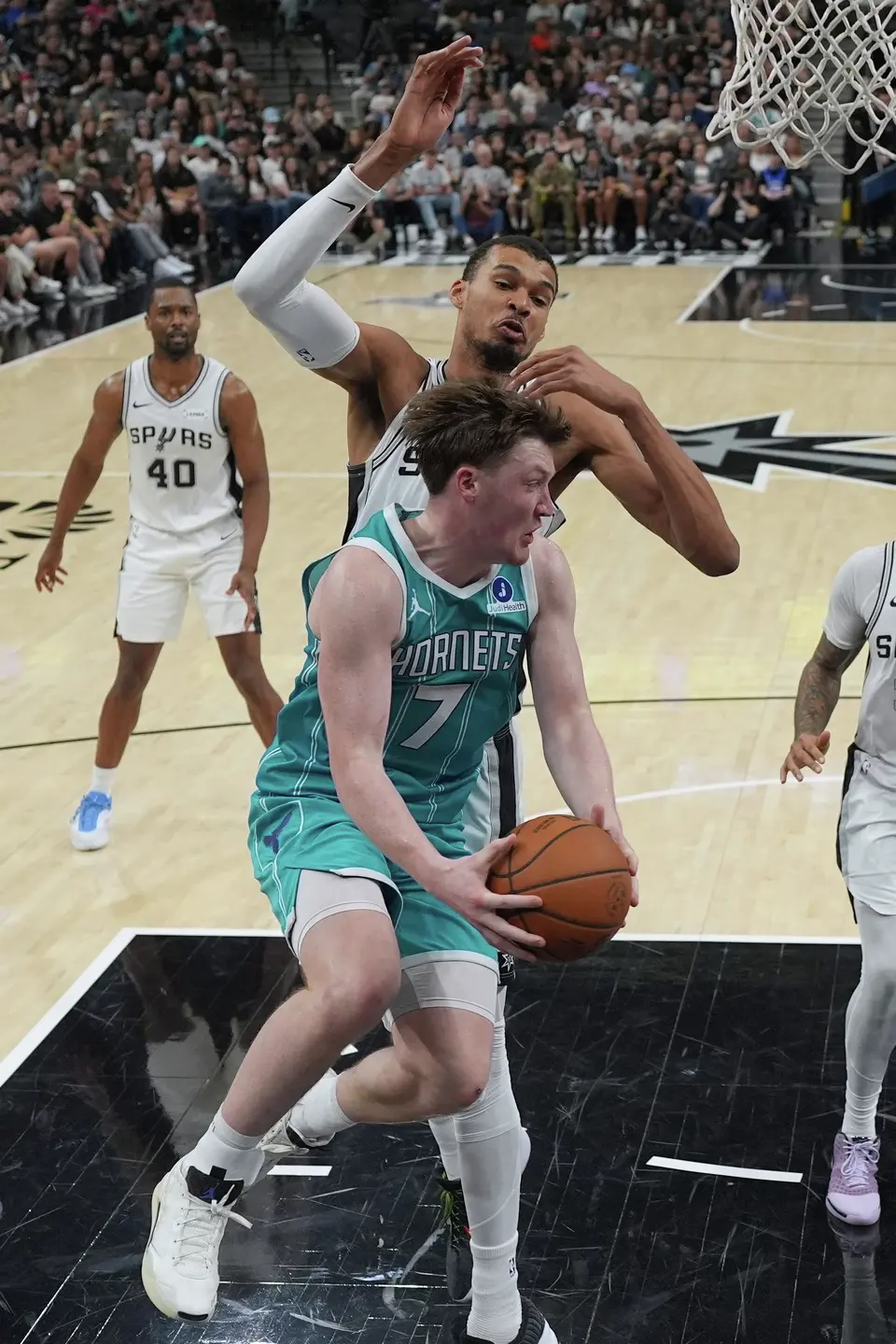 Charlotte Hornets guard Kon Knueppel (7) drives past San Antonio Spurs forward Victor Wembanyama (1) during the second half of an NBA basketball game in San Antonio, Saturday, March 14, 2026. (AP Photo/Eric Gay)