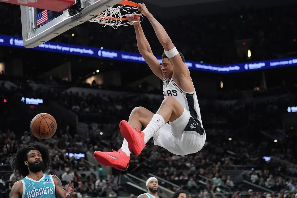 San Antonio Spurs forward Carter Bryant (11) scores over Charlotte Hornets guard Coby White (3) during the first half of an NBA basketball game in San Antonio, Saturday, March 14, 2026. (AP Photo/Eric Gay)