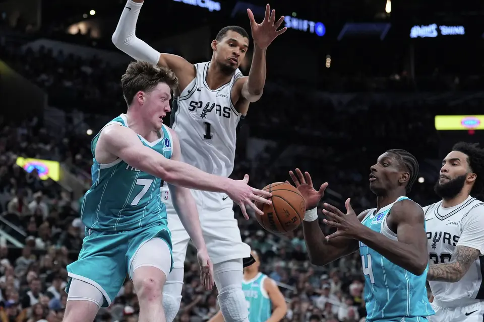 Charlotte Hornets guard Kon Knueppel (7) is pressured by San Antonio Spurs forward Victor Wembanyama (1) as he passes to teammate guard Sion James (4) during the second half of an NBA basketball game in San Antonio, Saturday, March 14, 2026. (AP Photo/Eric Gay)