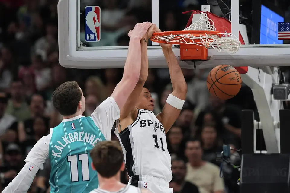 San Antonio Spurs forward Carter Bryant, right, scores past Charlotte Hornets center Ryan Kalkbrenner, left, during the second half of an NBA basketball game in San Antonio, Saturday, March 14, 2026. (AP Photo/Eric Gay)