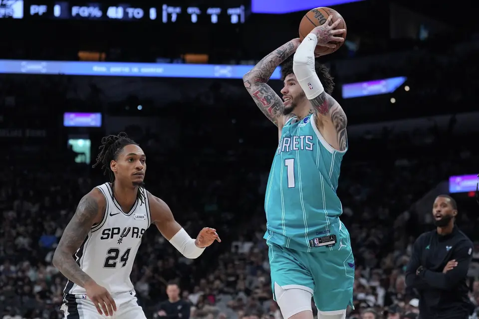 Charlotte Hornets guard LaMelo Ball (1) looks to pass around San Antonio Spurs guard Devin Vassell (24) during the second half of an NBA basketball game in San Antonio, Saturday, March 14, 2026. (AP Photo/Eric Gay)