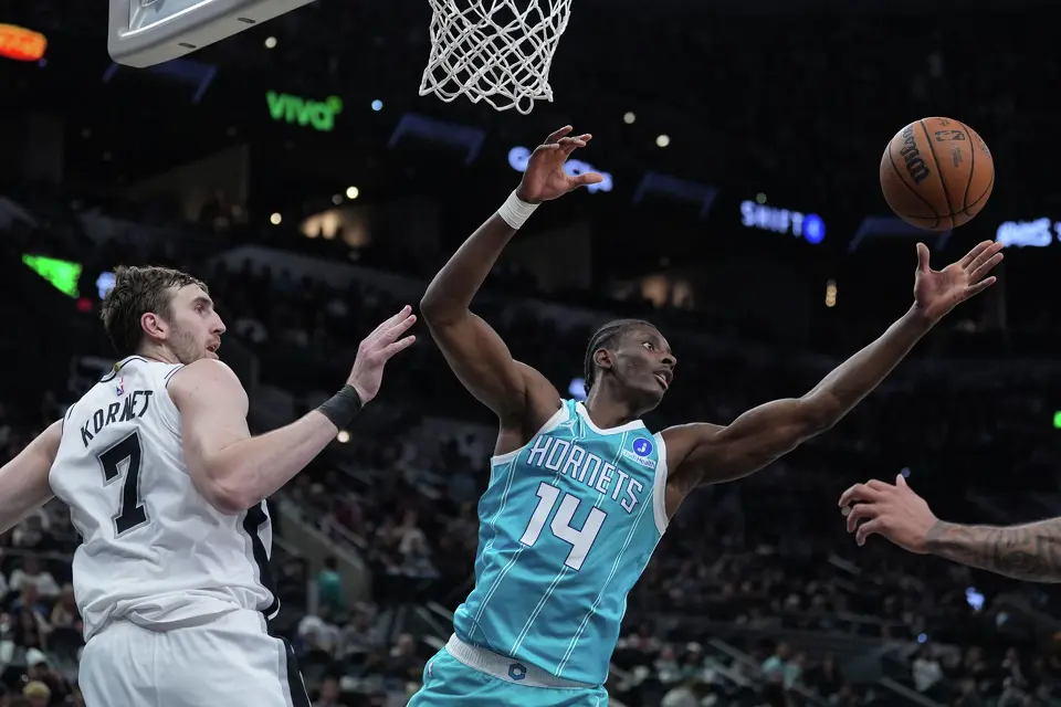 Charlotte Hornets forward Moussa Diabate (14) reaches past San Antonio Spurs center Luke Kornet (7) for a rebound during the second half of an NBA basketball game in San Antonio, Saturday, March 14, 2026. (AP Photo/Eric Gay)