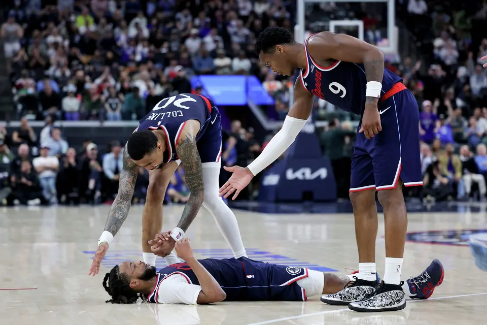 Los Angeles Clippers guard Darius Garland, bottom is helped up by forward John Collins, top left, and guard Bennedict Mathurin after drawing an and-one foul during the second half of an NBA basketball game against the San Antonio Spurs Monday, March 16, 2026, in Inglewood, Calif. (AP Photo/Ryan Sun)