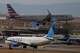 An American Airlines jetliner lands on a runway as a United Airlines plane waits for clearance to take off as high winds strafe Denver International Airport, Thursday, March 12, 2026, in Denver.
