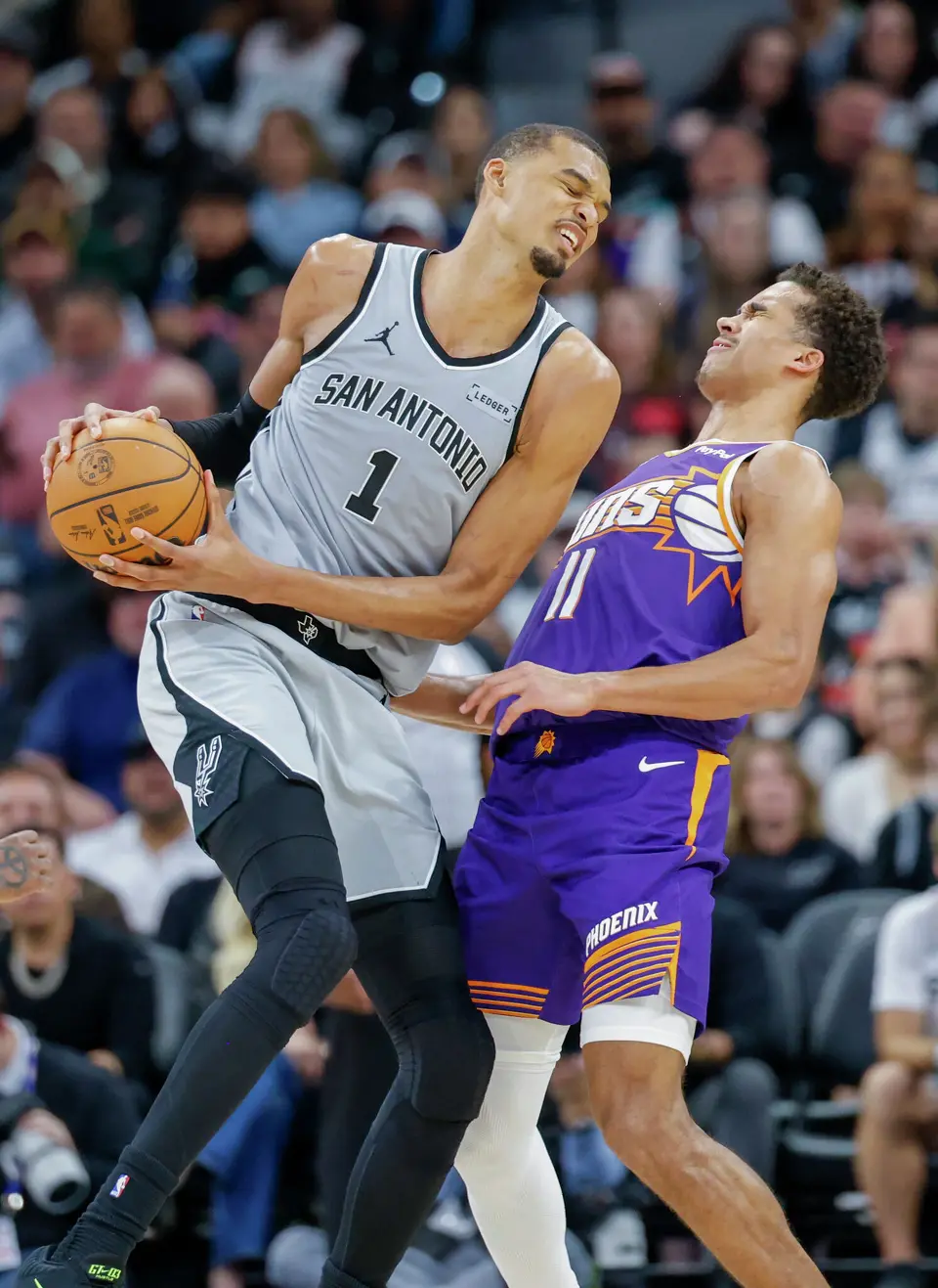 San Antonio Spurs forward Victor Wembanyama (1) is guarded by Phoenix Suns forward Oso Ighodaro (11) at Frost Bank Center in San Antonio, Thursday, March 19, 2026. The Spurs won in the last second, 101-100.