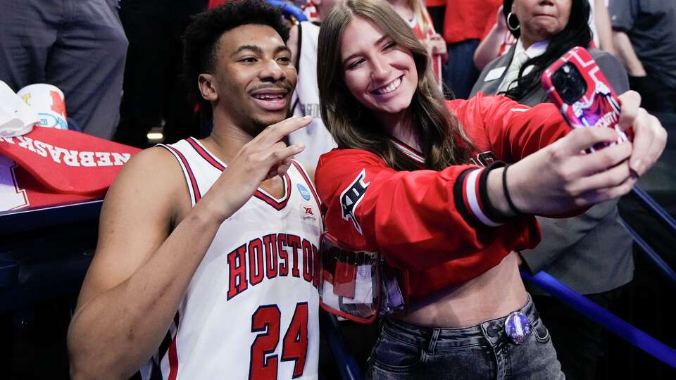 A Houston fan takes a photo with forward Chase McCarty after the team's 88-57 win over Texas A&M in the second round of the NCAA college basketball tournament in Oklahoma City, Saturday, March 21, 2026.