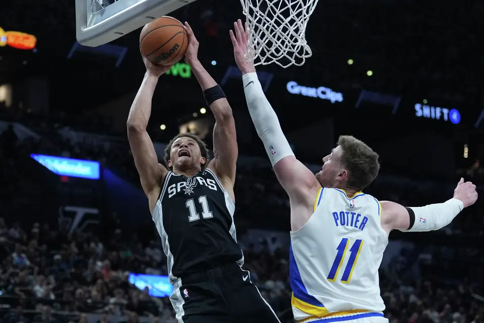 San Antonio Spurs forward Carter Bryant, left, drives to the basket against Indiana Pacers center Micah Potter, right, during the first half of an NBA basketball game in San Antonio, Saturday, March 21,2026. (AP Photo/Eric Gay)