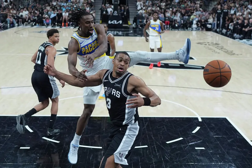 Indiana Pacers guard Aaron Nesmith, center, and San Antonio Spurs forward Keldon Johnson (3) scramble for a rebound during the second half of an NBA basketball game in San Antonio, Saturday, March 21,2026. (AP Photo/Eric Gay)