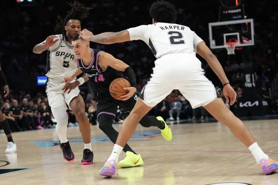 Miami Heat guard Tyler Herro (14) drives to the basket as San Antonio Spurs guard Stephon Castle (5) and guard Dylan Harper (2) defend during the second half of an NBA basketball game, Monday, March 23, 2026, in Miami. (AP Photo/Lynne Sladky)