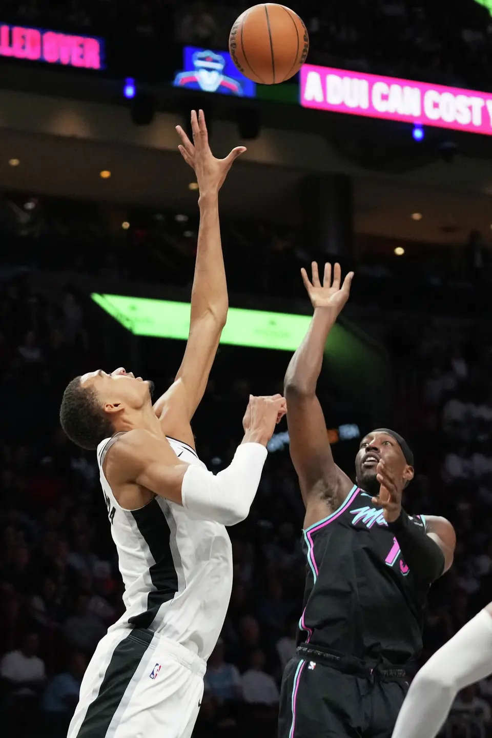 Miami Heat center Bam Adebayo, right, shoots over San Antonio Spurs forward Victor Wembanyama, left, during the second half of an NBA basketball game, Monday, March 23, 2026, in Miami. (AP Photo/Lynne Sladky)