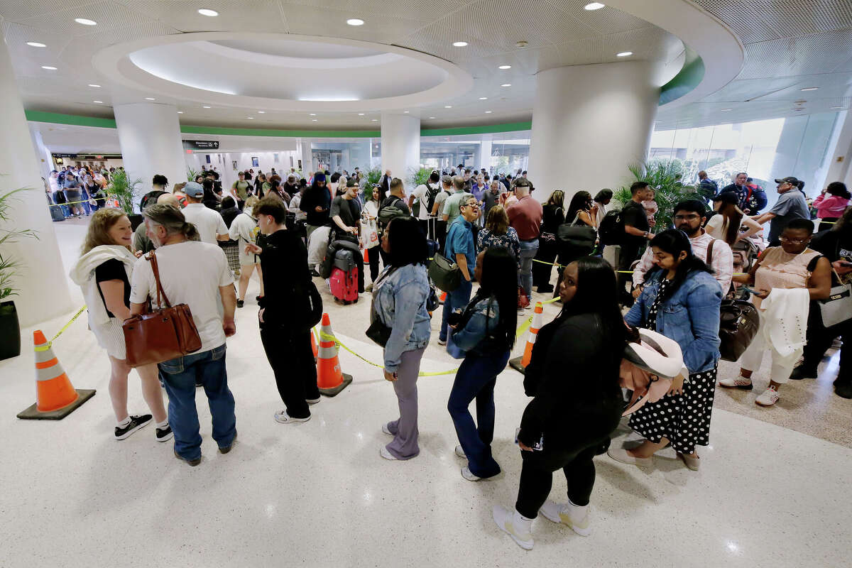 Air travelers wait in a long line that spirals across the open spaces, starting from the baggage claim area on the floor below the TSA security checkpoint in Terminal A at the George Bush Intercontinental Airport, Monday, March 23, 2026, in Houston. (AP Photo/Michael Wyke)