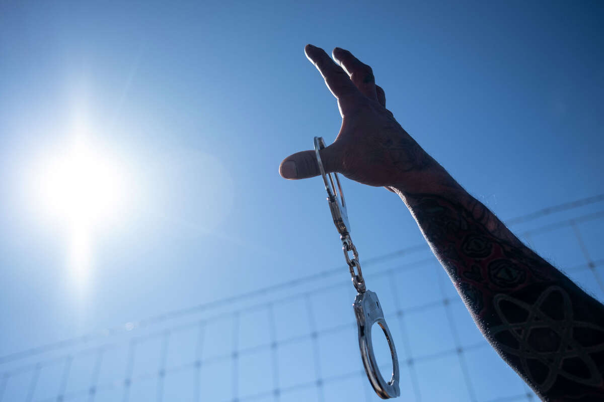 Robert David Padgett Jr. raises handcuffs in the air as they protest against Immigration and Customs Enforcement at the South Texas Family Residential Center on January 28, 2026 in Dilley, Texas. In March 2026, attorneys have filed a new brief alleging mistreatment and abuse at the Dilley facility.