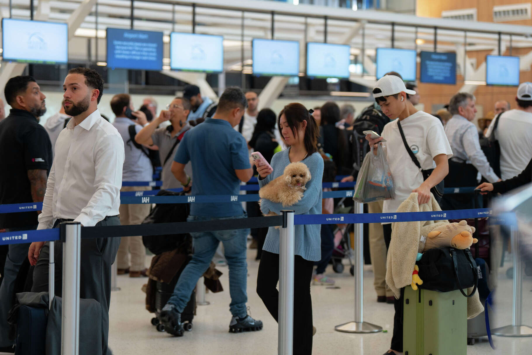 Kelly Huynh of Houston and her dog Luna wait in line with other air travelers as they progress to the TSA security checkpoint in Terminal E at the George Bush Intercontinental Airport, Tuesday, March 24, 2026, in Houston, TX.