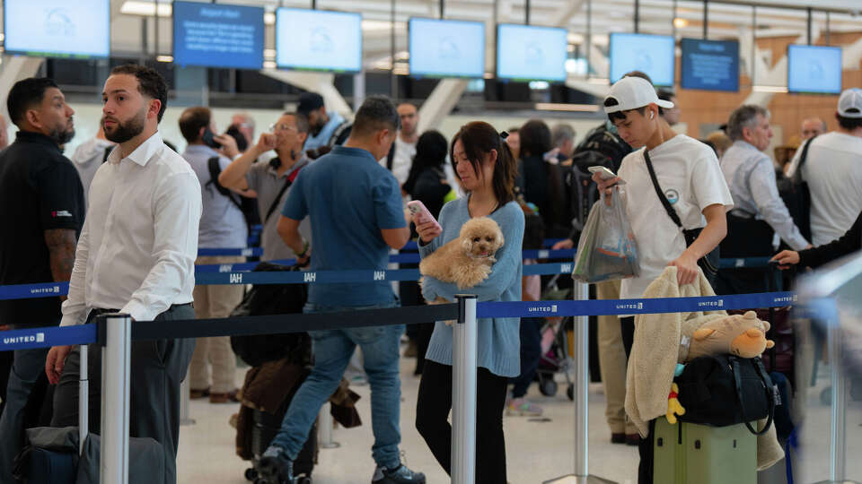 Kelly Huynh of Houston and her dog Luna wait in line with other air travelers as they progress to the TSA security checkpoint in Terminal E at the George Bush Intercontinental Airport, Tuesday, March 24, 2026, in Houston, TX.