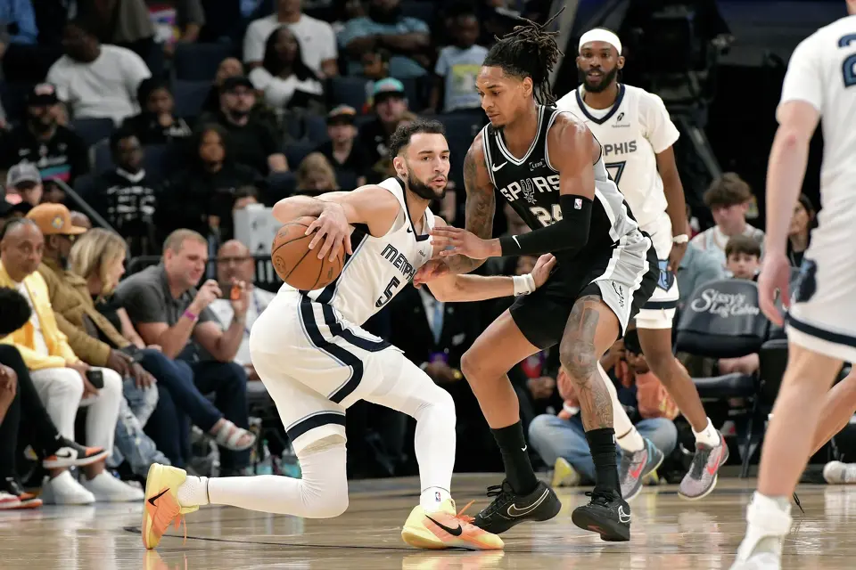 Memphis Grizzlies forward Tyler Burton (5) handles the ball against San Antonio Spurs guard Devin Vassell (24) in the second half of an NBA basketball game Wednesday, March 25, 2026, in Memphis, Tenn. (AP Photo/Brandon Dill)