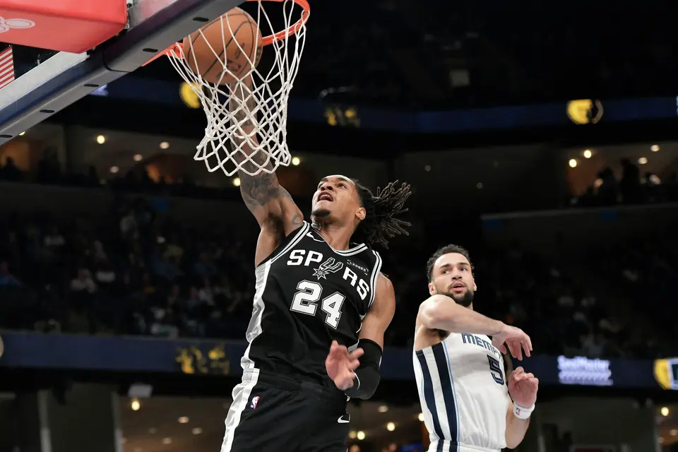 San Antonio Spurs guard Devin Vassell (24) dunks ahead of Memphis Grizzlies forward Tyler Burton (5) in the second half of an NBA basketball game Wednesday, March 25, 2026, in Memphis, Tenn. (AP Photo/Brandon Dill)
