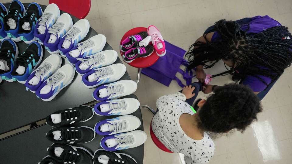 Volunteers help students select new shoes during a distribution event by FedEx and Operation Warm at Gregg Elementary School in Houston on Wednesday, March 25, 2026.