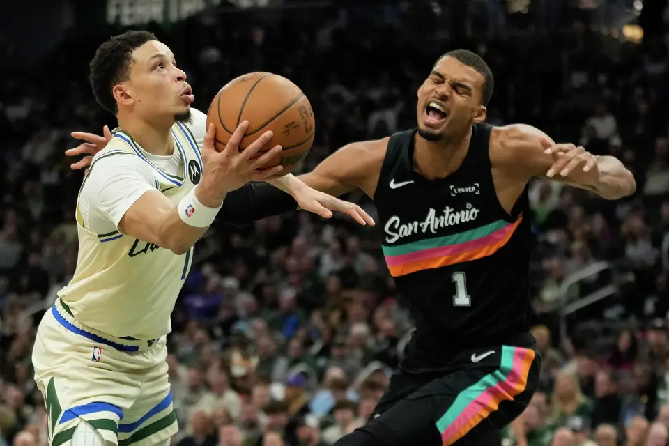 Milwaukee Bucks' Ryan Rollins, left, shoots against San Antonio Spurs' Victor Wembanyama during the first half of an NBA basketball game Saturday, March 28, 2026, in Milwaukee. (AP Photo/Aaron Gash)