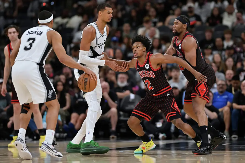 Chicago Bulls guard Collin Sexton (2) tangles with San Antonio Spurs center Victor Wembanyama, center left, during the second half of an NBA basketball game, Monday, March 30, 2026, in San Antonio. (AP Photo/Darren Abate)