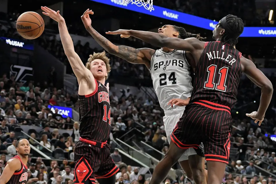 San Antonio Spurs guard Devin Vassell (24) tangles with Chicago Bulls players Leonard Miller (11) and Matas Buzelis (14) during the first half of an NBA basketball game, Monday, March 30, 2026, in San Antonio. (AP Photo/Darren Abate)