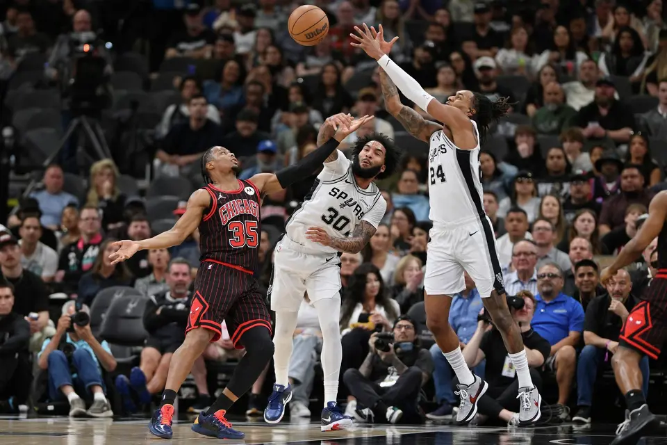 Chicago Bulls guard Isaac Okoro (35) tangles with San Antonio Spurs' Julian Champagnie (30) and Devin Vassell (24) during the first half of an NBA basketball game, Monday, March 30, 2026, in San Antonio. (AP Photo/Darren Abate)