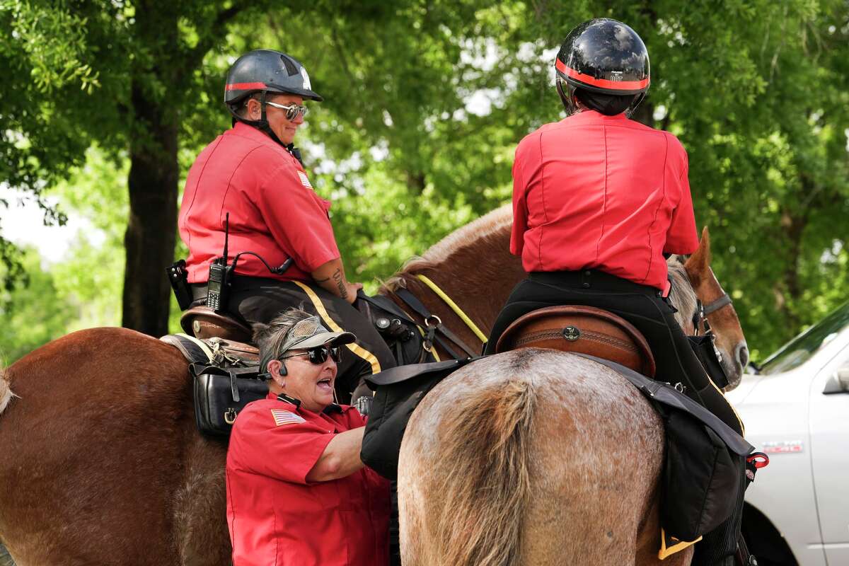 with Alpha & Omega Services Lt. Michelle Castle, center, helps adjust the Maisie Terrell’s equipment as they patrol around The Woodlands Mall, Tuesday, March 31, 2026, in The Woodlands.
