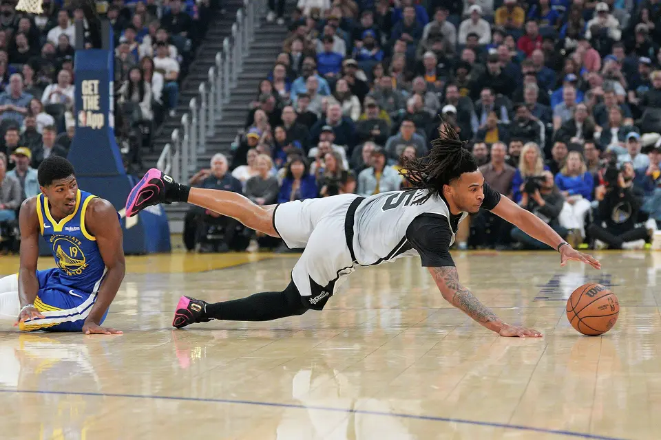 San Antonio Spurs guard Stephon Castle (5) dives for the ball against Golden State Warriors guard Nate Williams (19) during the first half of an NBA basketball game in San Francisco, Wednesday, April 1, 2026. (AP Photo/Tony Avelar)