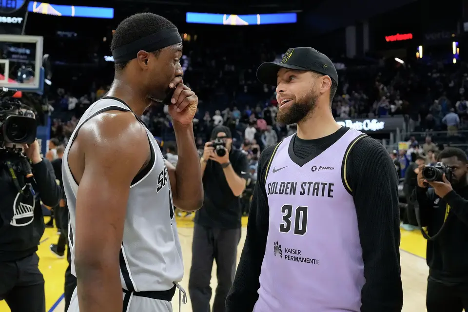 Injured Golden State Warriors guard Stephen Curry, right, talks with San Antonio Spurs forward Harrison Barnes after an NBA basketball game in San Francisco, Wednesday, April 1, 2026. (AP Photo/Tony Avelar)