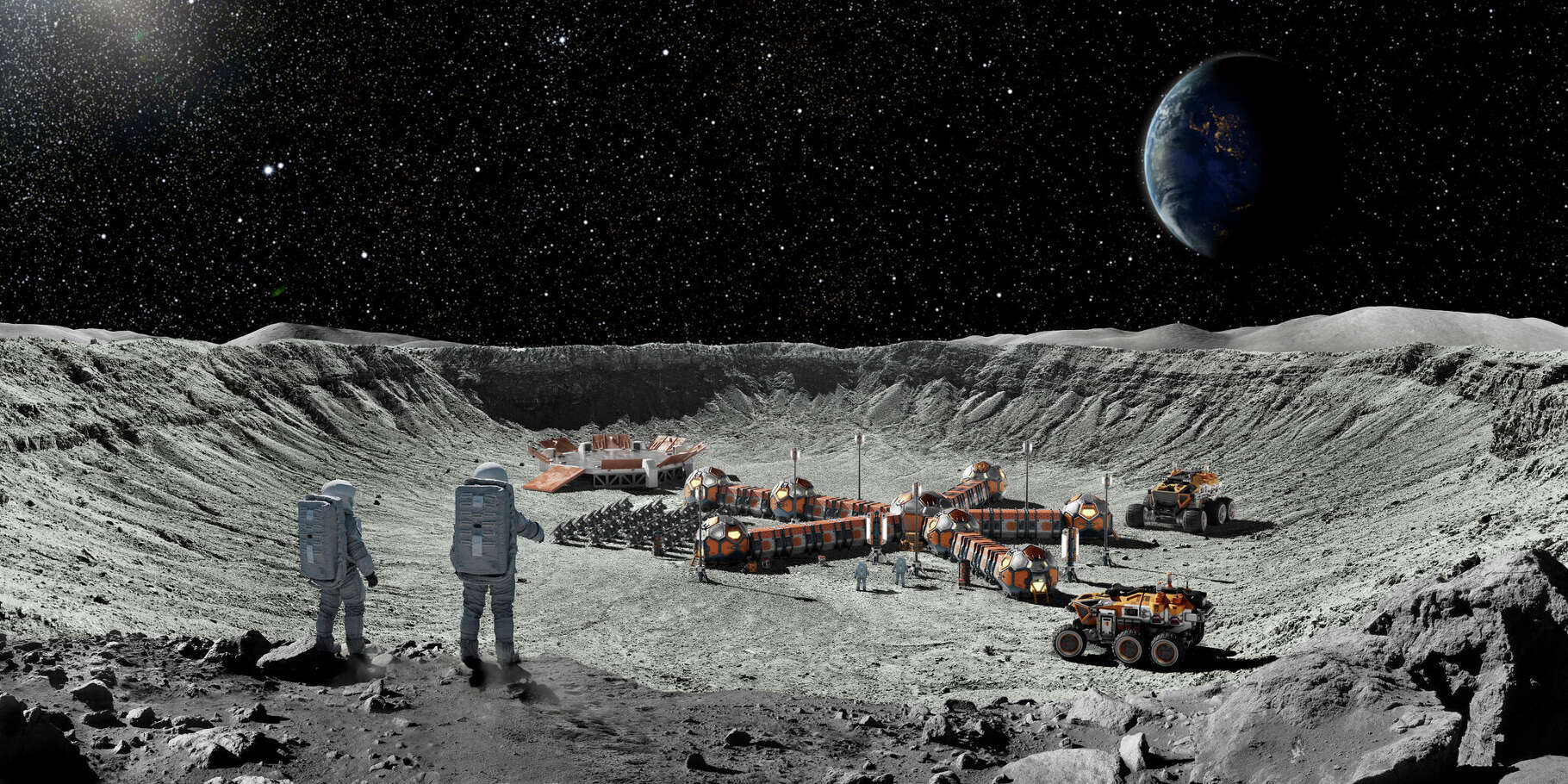 Wide angle view from behind two astronauts with backpacks standing at the edge of a large crater looking down on a moon base with solar panels, modular habitation units, rover vehicles and a launch pad.