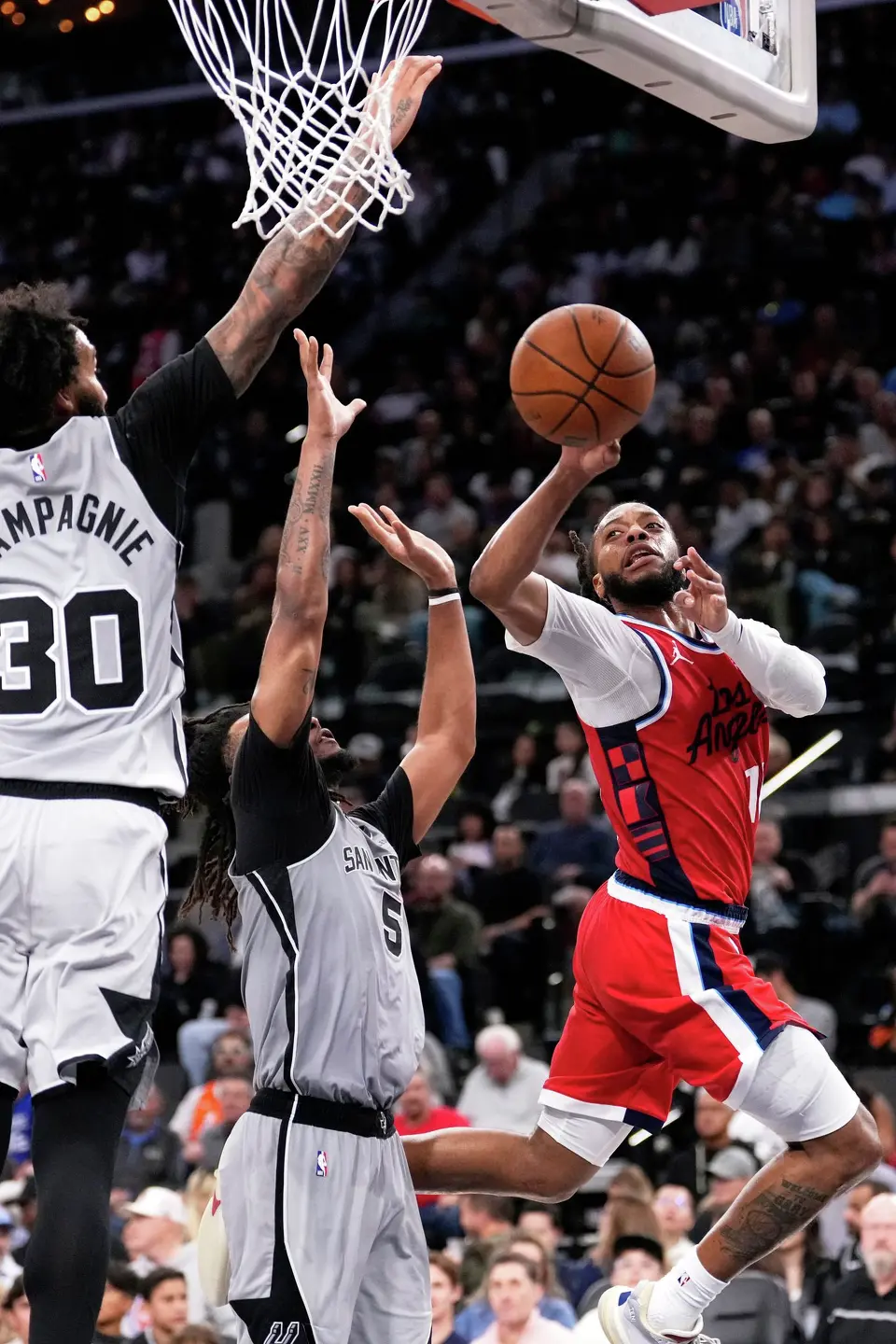 Los Angeles Clippers guard Darius Garland, right, shoots as San Antonio Spurs forward Julian Champagnie, left, and guard Stephon Castle defend during the second half of an NBA basketball game Thursday, April 2, 2026, in Inglewood, Calif. (AP Photo/Mark J. Terrill)