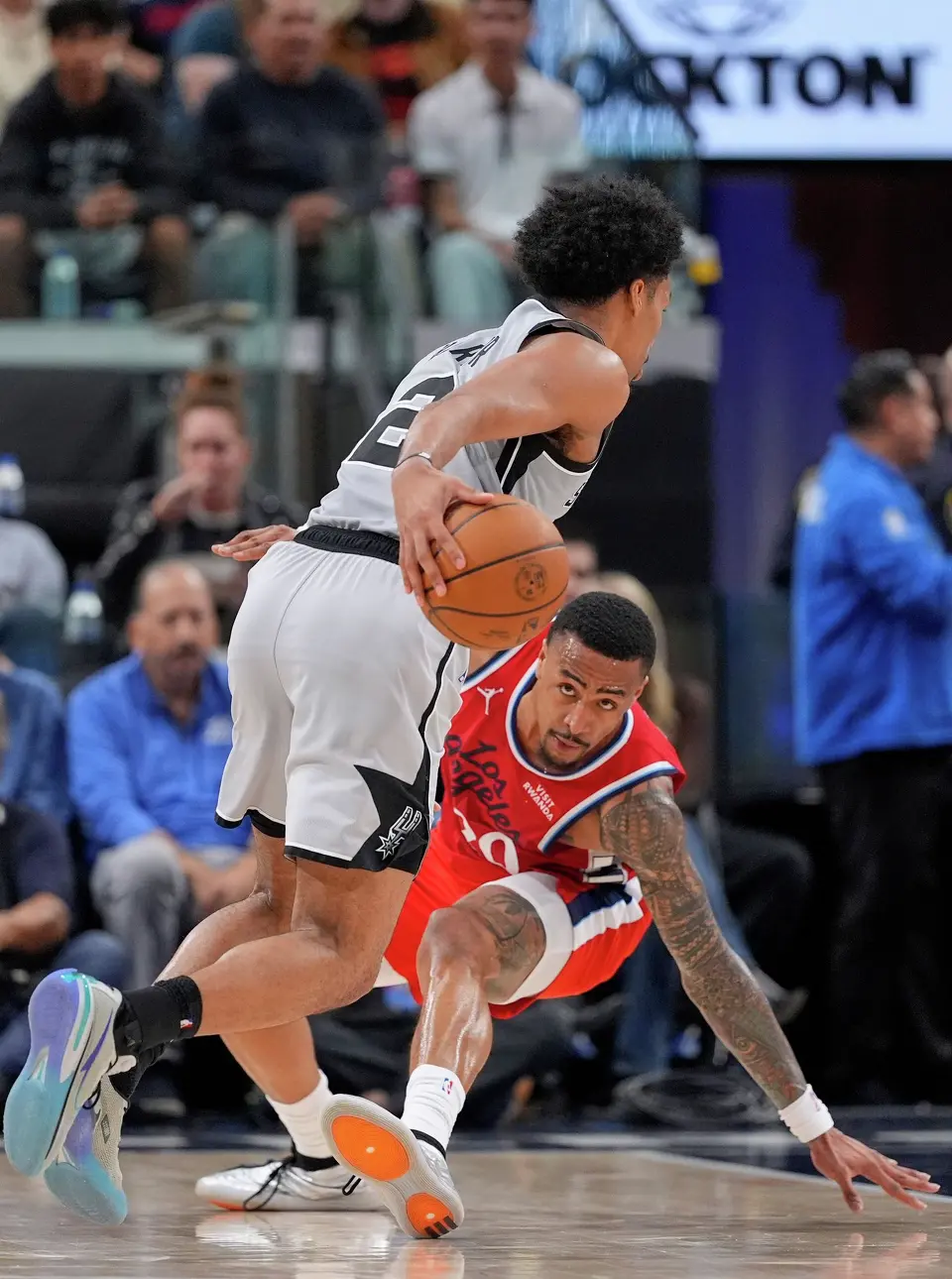 San Antonio Spurs guard Dylan Harper, top, drives by Los Angeles Clippers forward John Collins during the second half of an NBA basketball game Thursday, April 2, 2026, in Inglewood, Calif. (AP Photo/Mark J. Terrill)