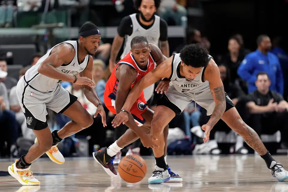 San Antonio Spurs guard De'aaron Fox, left, and guard Dylan Harper, right, go after a loose ball along with Los Angeles Clippers guard Kris Dunn during the first half of an NBA basketball game Thursday, April 2, 2026, in Inglewood, Calif. (AP Photo/Mark J. Terrill)