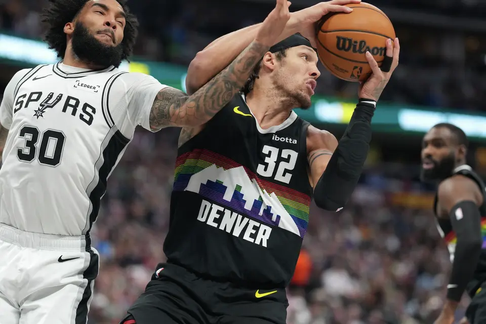 Denver Nuggets forward Aaron Gordon, right, pulls in a loose ball as San Antonio Spurs forward Julian Champagnie defends in the first half of an NBA basketball game Saturday, April 4, 2026, in Denver. (AP Photo/David Zalubowski)