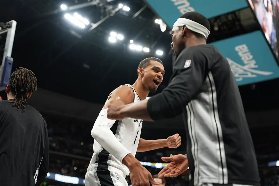 San Antonio Spurs center Victor Wembanyama, back, greets teammates before an NBA basketball game against the Denver Nuggets, Saturday, April 4, 2026, in Denver. (AP Photo/David Zalubowski)