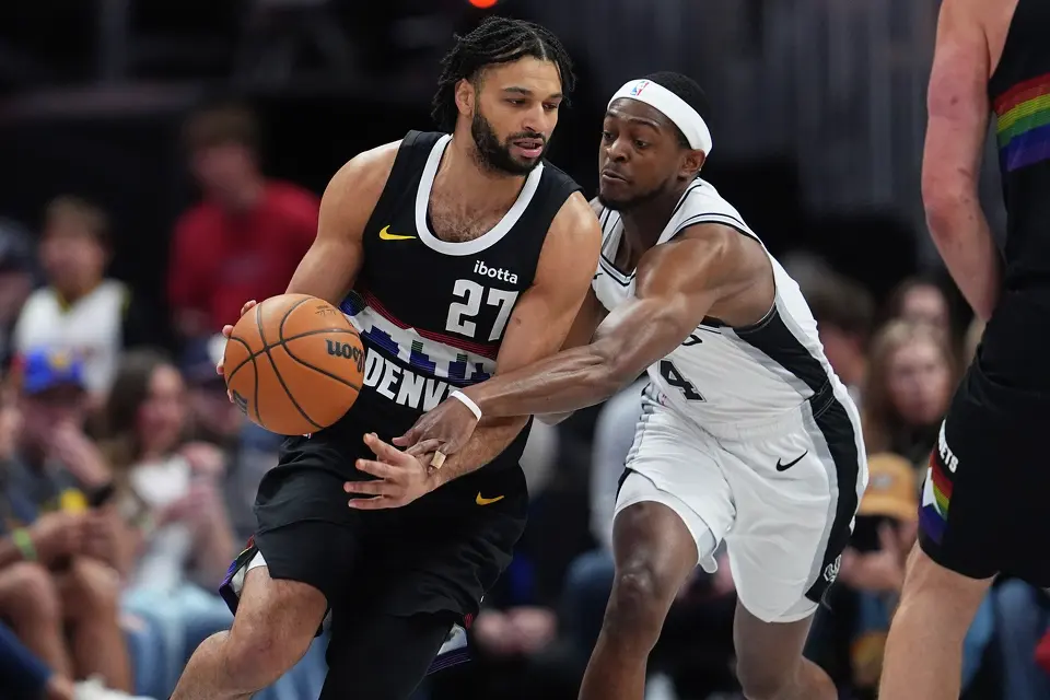 Denver Nuggets guard Jamal Murray, left, drives past San Antonio Spurs guard De'aaron Fox in the first half of an NBA basketball game Saturday, April 4, 2026, in Denver. (AP Photo/David Zalubowski)