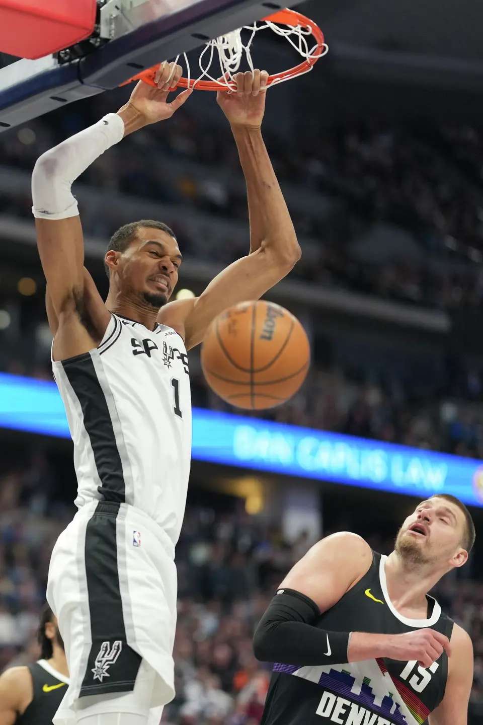 San Antonio Spurs center Victor Wembanyama, left, dunks over Denver Nuggets center Nikola Jokic in the first half of an NBA basketball game Saturday, April 4, 2026, in Denver. (AP Photo/David Zalubowski)