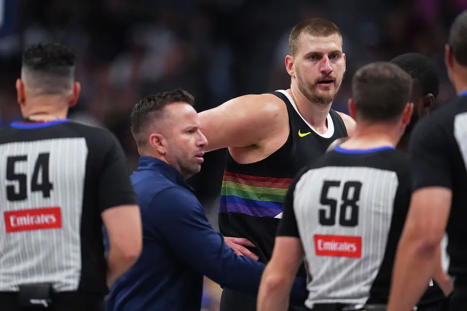 Denver Nuggets center Nikola Jokic, back right, argues for a call after being hit in the nose as assistant coach J.J. Barea, back left, intercedes with referees Ray Acosta, front left, and Josh Tiven in the first half of an NBA basketball game against the San Antonio Spurs, Saturday, April 4, 2026, in Denver. (AP Photo/David Zalubowski)