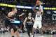 San Antonio Spurs guard Devin Vassell, right, shoots over Denver Nuggets guard Christian Braun (0) and center Nikola Jokic in the first half of an NBA basketball game Saturday, April 4, 2026, in Denver. (AP Photo/David Zalubowski)