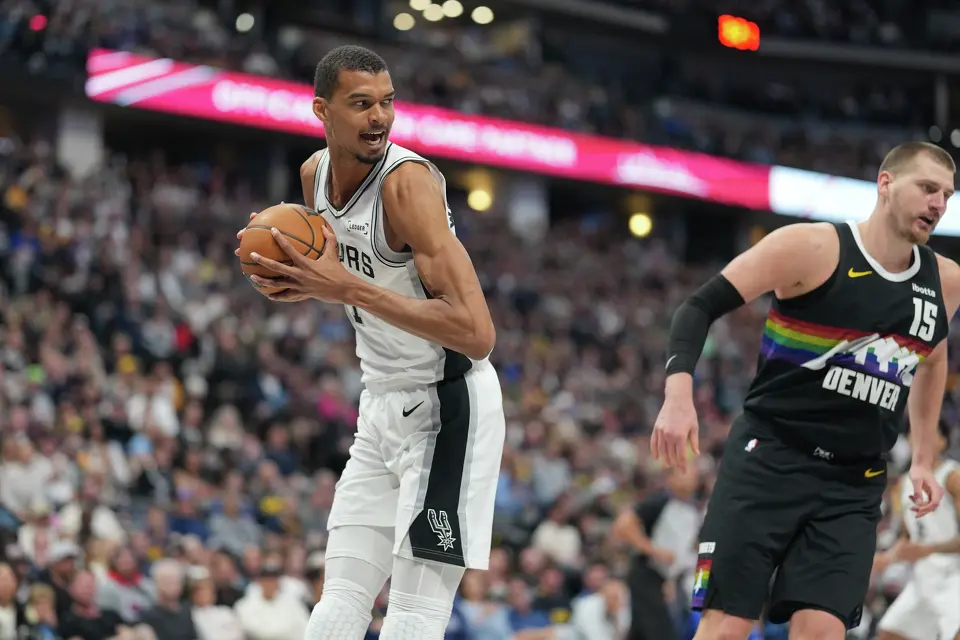 San Antonio Spurs center Victor Wembanyama, pulls in a rebound next to Denver Nuggets center Nikola Jokic in the second half of an NBA basketball game Saturday, April 4, 2026, in Denver. (AP Photo/David Zalubowski)