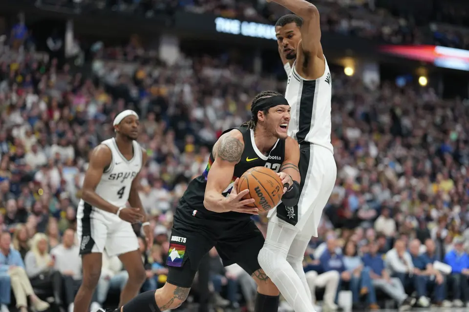 Denver Nuggets forward Aaron Gordon, left, drives under San Antonio Spurs center Victor Wembanyama in the second half of an NBA basketball game Saturday, April 4, 2026, in Denver. (AP Photo/David Zalubowski)
