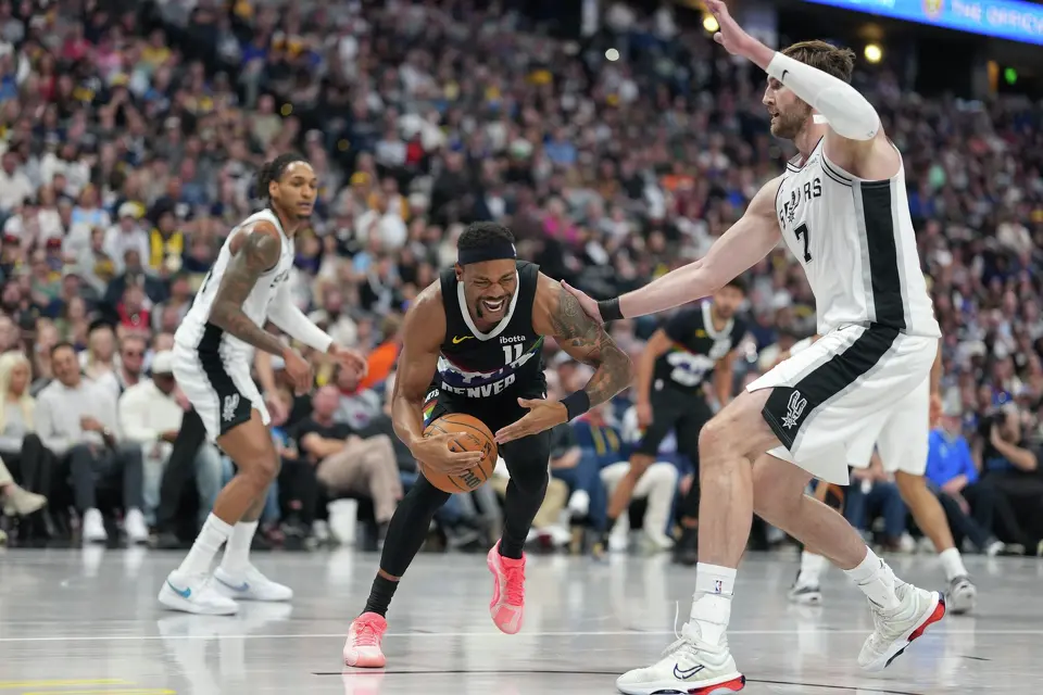 Denver Nuggets guard Bruce Brown, left, reacts after being injured while driving past San Antonio Spurs forward Luke Kornet in the second half of an NBA basketball game Saturday, April 4, 2026, in Denver. (AP Photo/David Zalubowski)