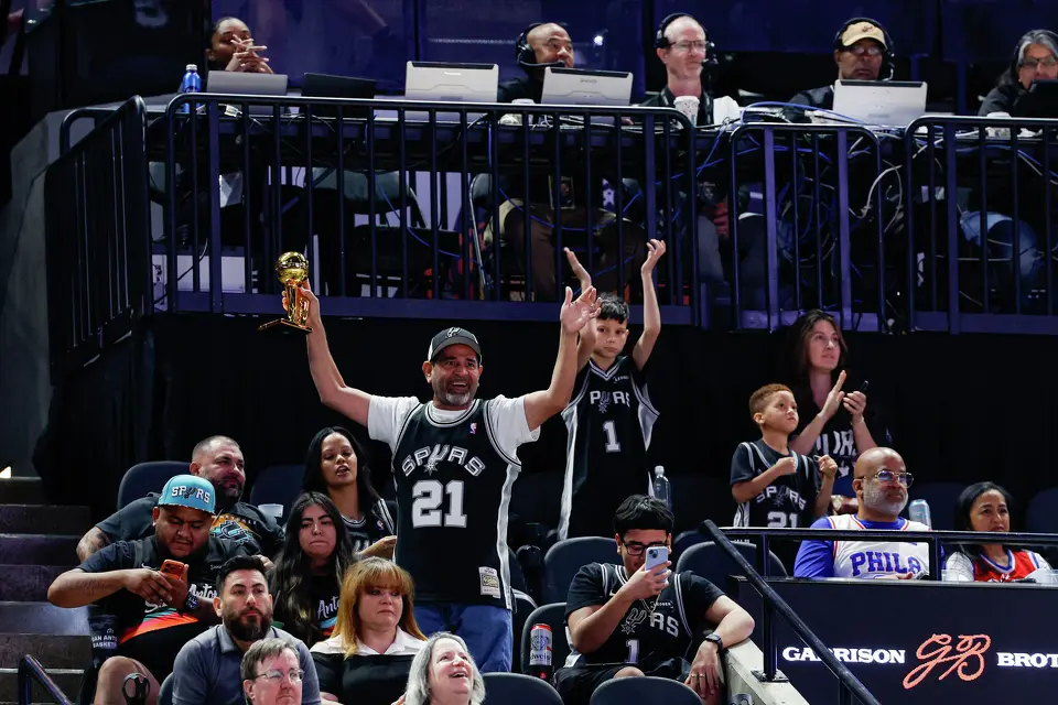 A San Antonio Spurs fan dances and waves a championship trophy as the Spurs close in on their 60th regular-season victory against the Philadelphia 76ers at Frost Bank Center in San Antonio on Monday, April 6, 2026. The Spurs won 115-102.