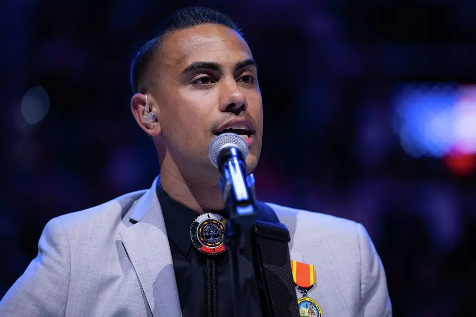 San Antonio Spurs TV play-by-play announcer Jacob Tobey performs the national anthem during Native American Heritage Night before an NBA game against the Philadelphia 76ers at Frost Bank Center in San Antonio on Monday, April 6, 2026.