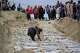 A man places stones on graves during a second mass funeral for victims of an earlier airstrike on a drug rehabilitation center, in Kabul, Afghanistan, Thursday, March 26, 2026.