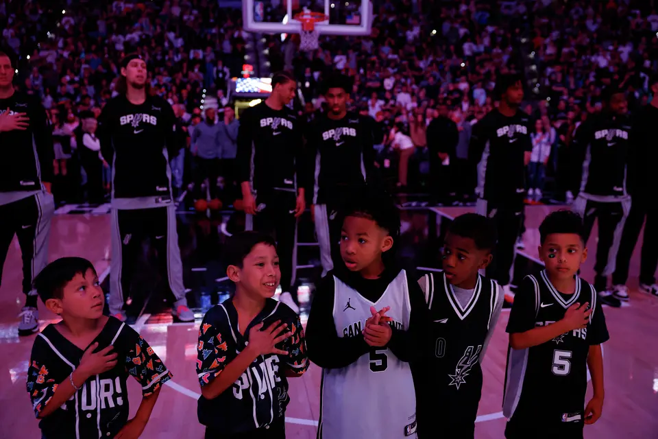 Young San Antonio Spurs dfans stand on the court, in front of the team, during the playing of the national anthem before a home game against the Portland Trail Blazers at Frost Bank Center in San Antonio, Wednesday, April 8, 2026.