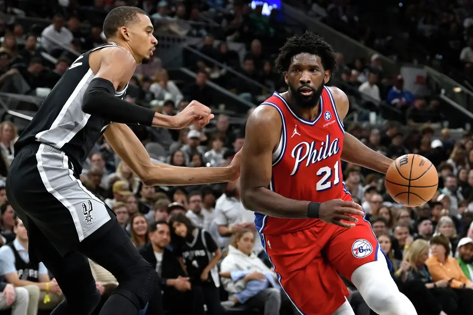 Joel Embiid (21) de los 76ers de Filadelfia penetra hacia la canasta ante Victor Wembanyama (izquierda) de los Spurs de San Antonio, el lunes 6 de abril de 2026. (AP Foto/Darren Abate)